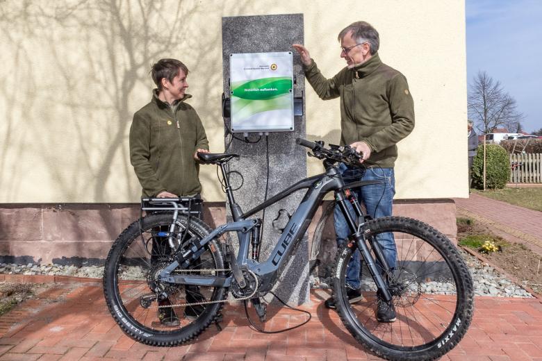 Claudia Wilhelm und Uwe Müller (beide Naturparkverwaltung) präsentieren die neue E-Bike Ladestation am Verwaltungssitz in Fürstenhagen